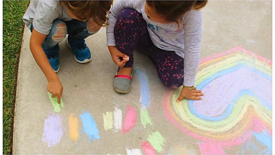 Children making colorful sidewalk chalk art for Love in Action